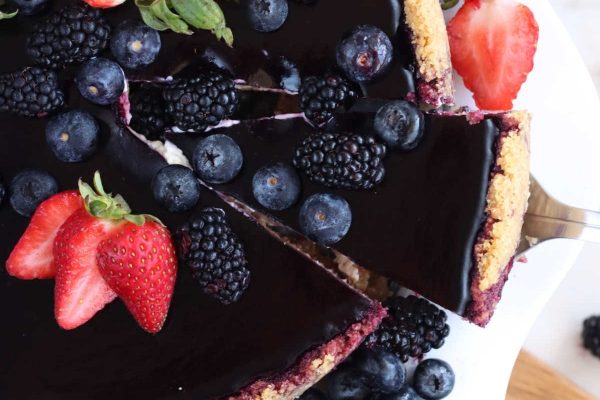 A blueberry cheesecake with berries on a white plate.