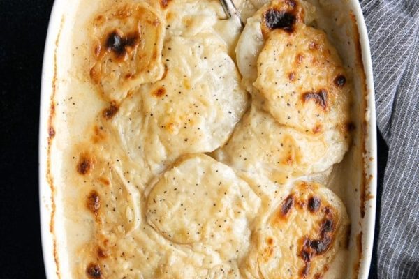 Scalloped potatoes in a white baking dish.