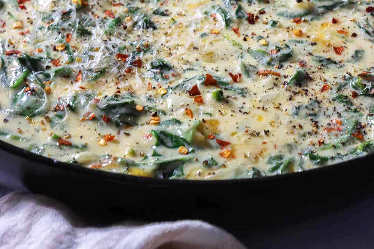Creamy spinach dip in a black bowl.