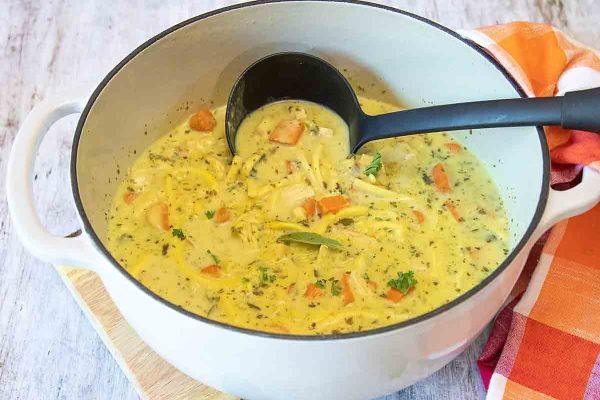 Creamy leftover chicken soup on a white Dutch oven. 