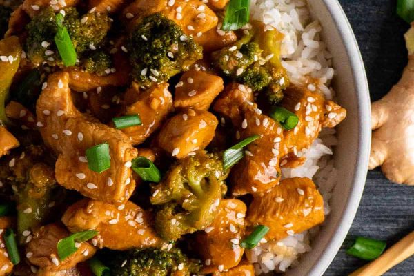 Crockpot chicken and broccoli in white bowl with chopsticks.