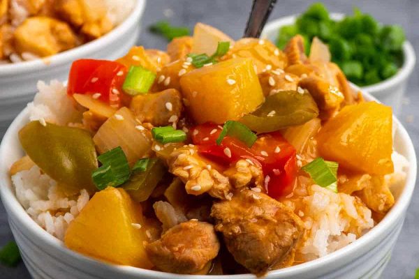 Crockpot Hawaiian chicken in a white bowl with chopsticks.