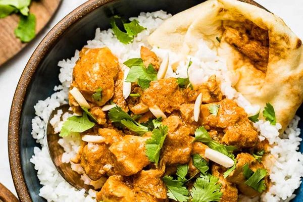 Slow cooker butter chicken with rice in a brown bowl.