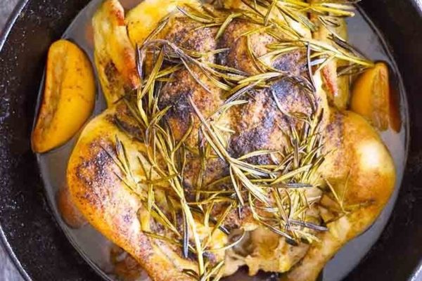 Whole chicken with herbs baked in black pot.