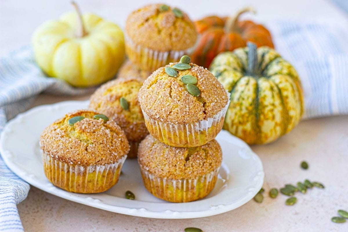 Pumpkin muffins with pumpkin seeds on them.