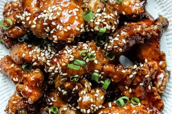 Saucy chunks of crispy chicken with sesame seeds over top.