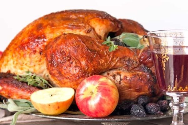 Fig-spiced whole turkey served on a dish with fruits. 