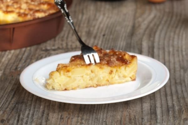 A slice of apple cake on a plate with a fork.