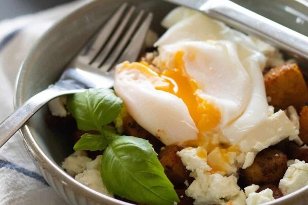 Fried potatoes and sunny side up eggs in a bowl.