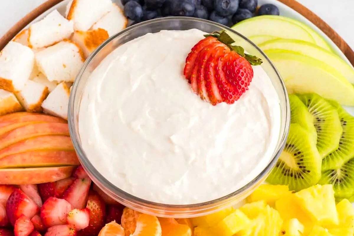 A round platter with a dip and fresh cut fruit.