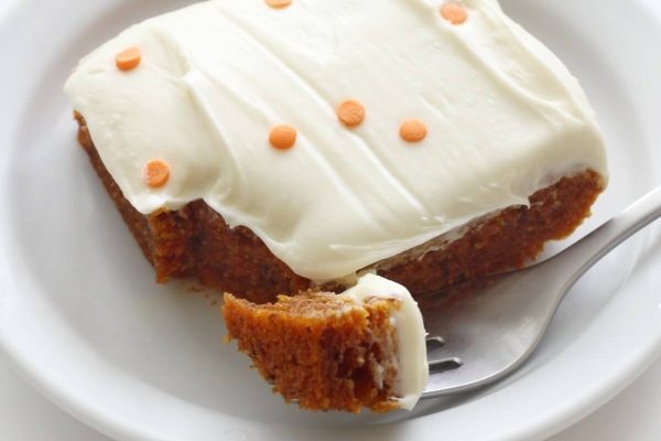 Slice of pumpkin cake with white frosting.