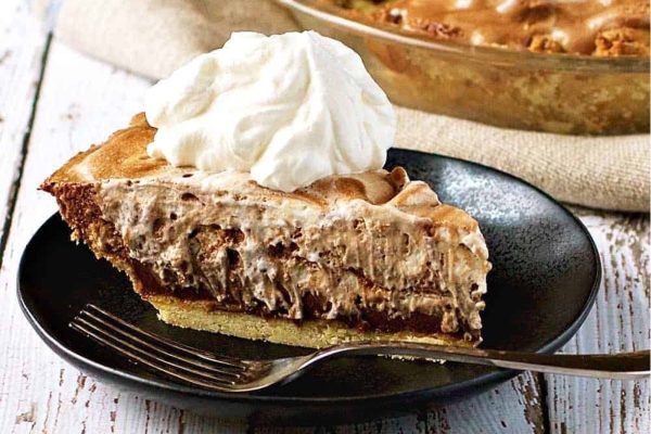 A slice of chocolate rum pie on a plate with whipped cream.