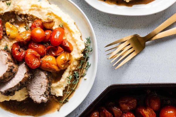 A plate with meat, mashed potatoes and tomatoes.