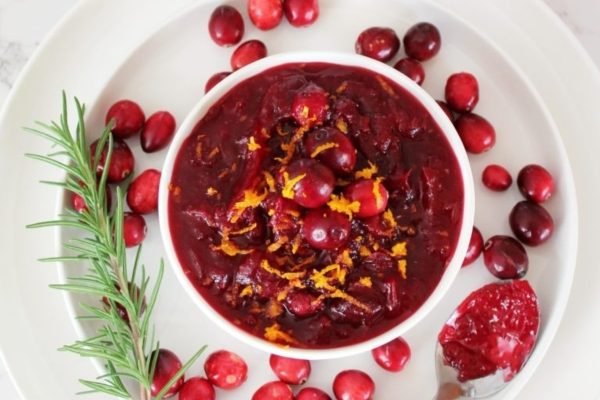 Homemade Cranberry Sauce on a round plate with cranberries. 