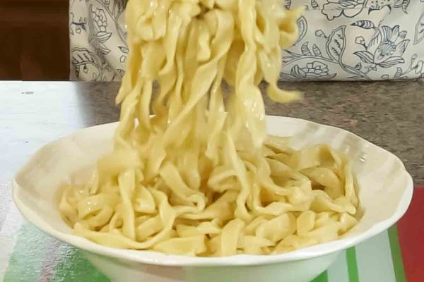A person pouring noodles into a bowl.