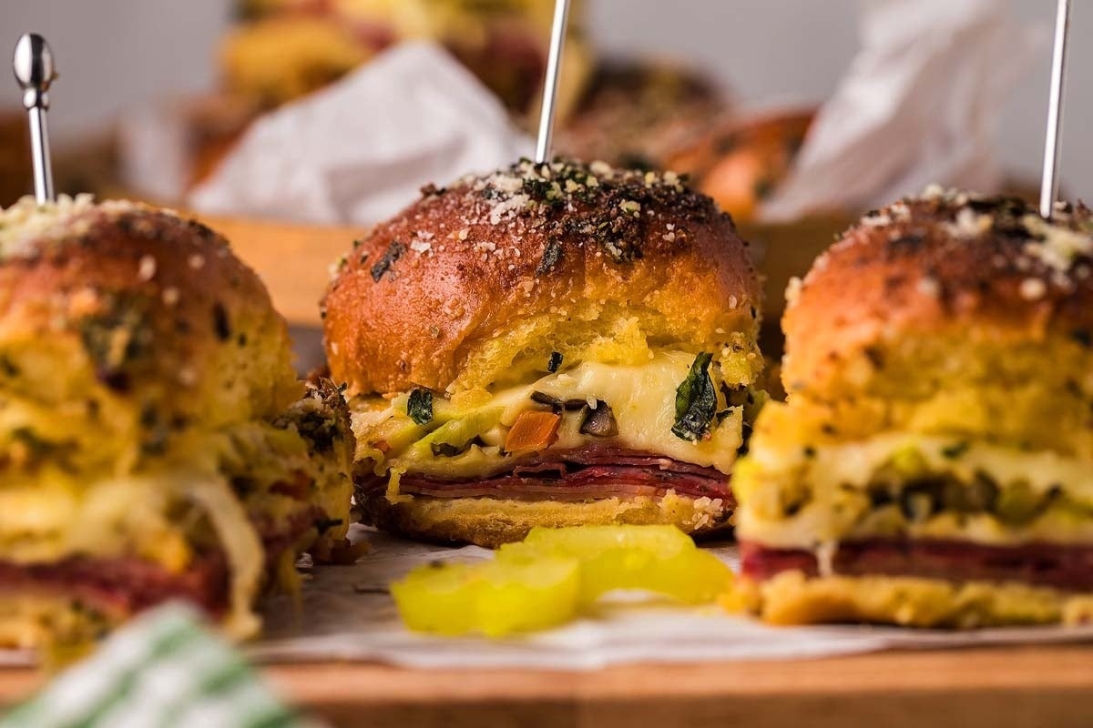 Ham and cheese sliders on a wooden board.