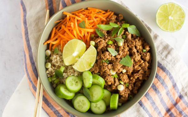 Beef in a green bowl with cucumber and carrots.