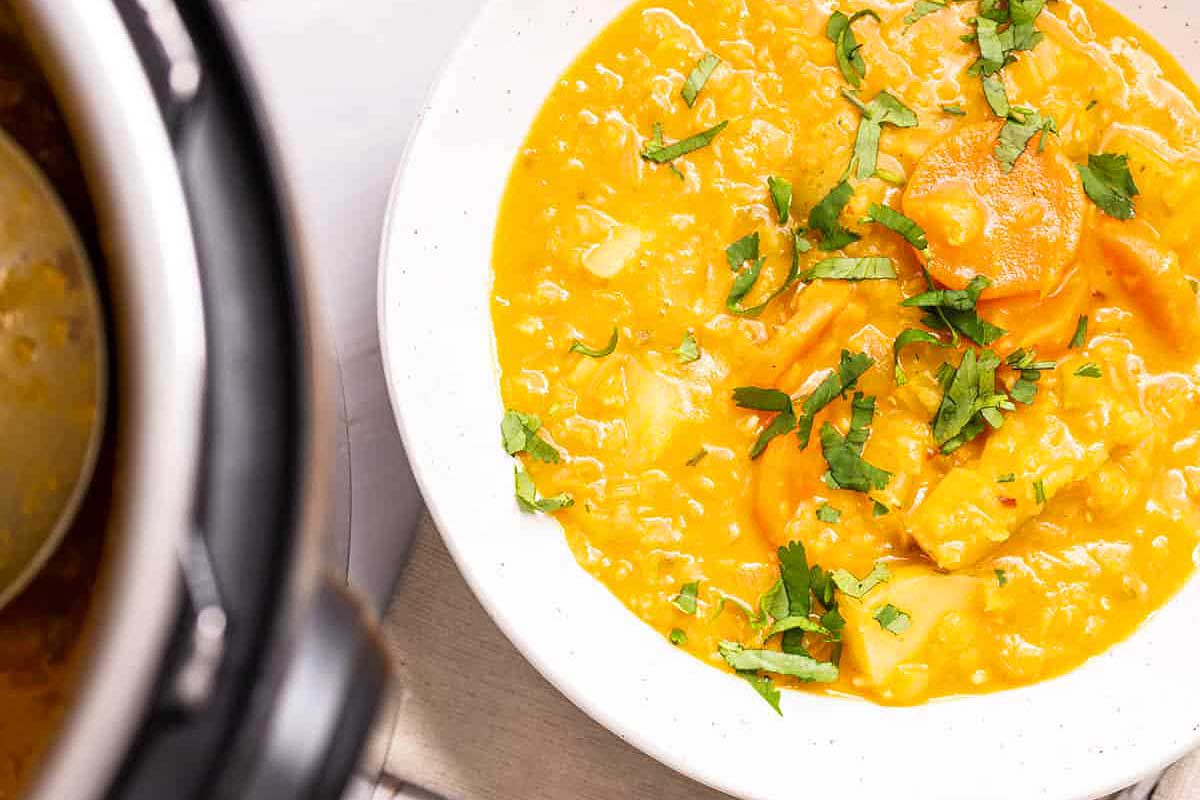 A bowl of soup in front of an instant pot.