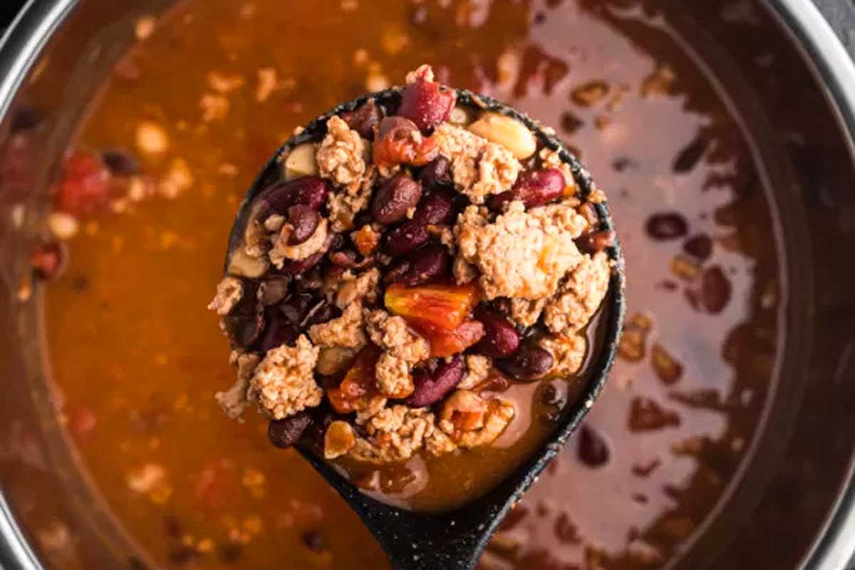 A spoon full of chili and beans in an instant pot.