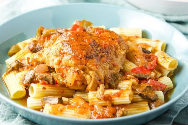 A bowl of pasta with chicken and vegetables in it.