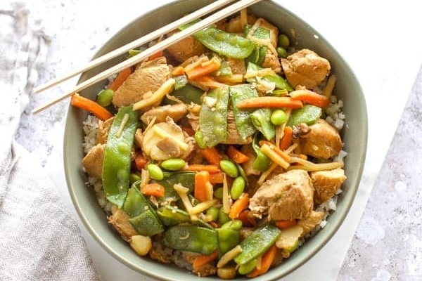 A bowl of Instant Pot Chicken Stir Fry with chopsticks.