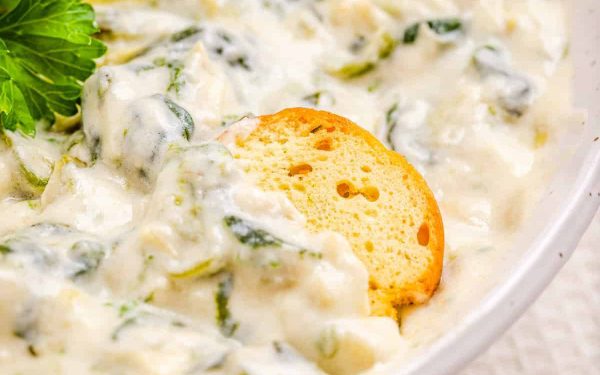 Spinach dip with a piece of bread dipped in.