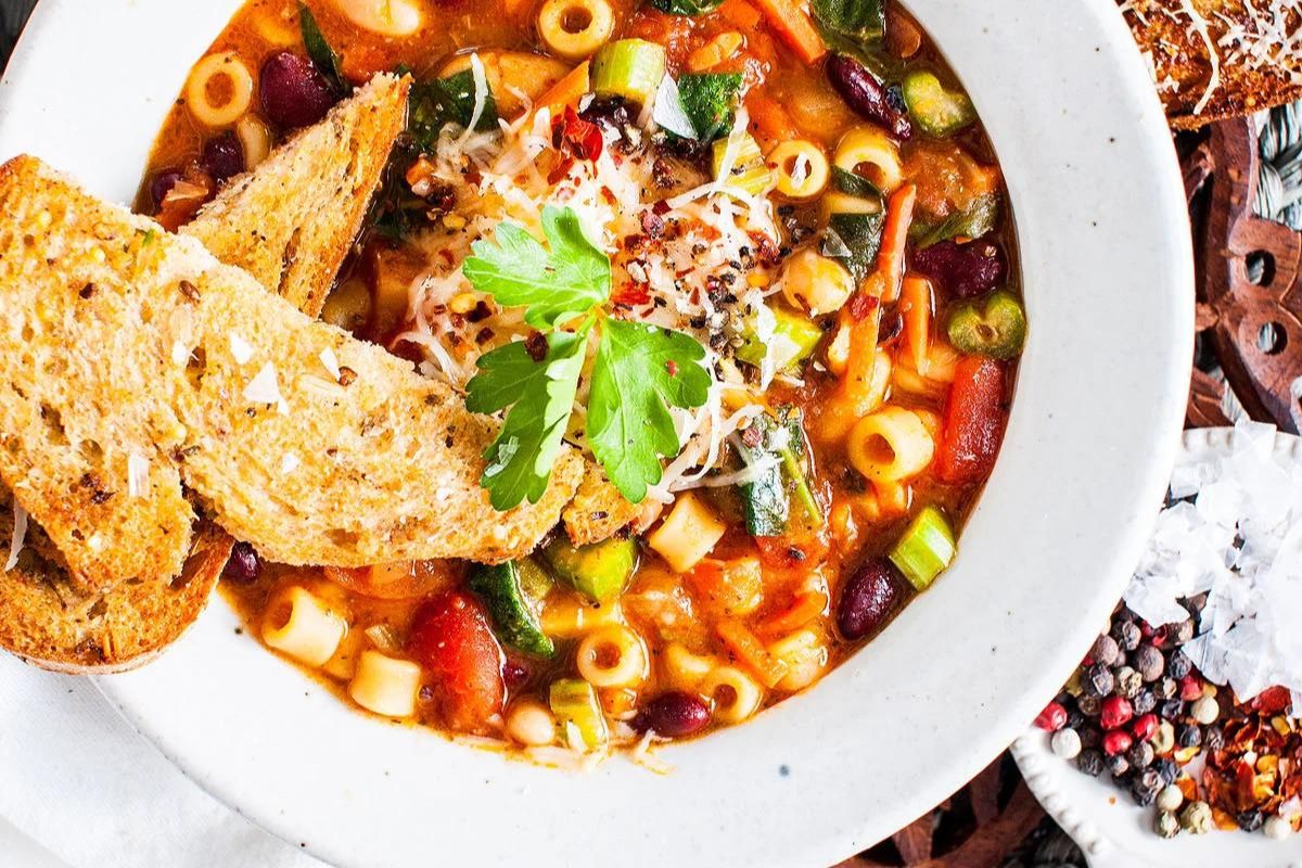 Italian Minestrone Soup with bread in a white bowl.