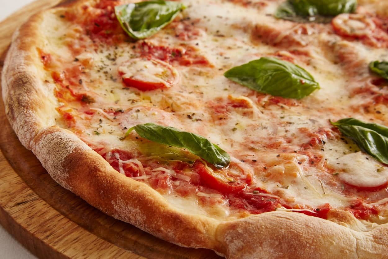 Italy’s Pizza Margherita with basil on a wooden board.