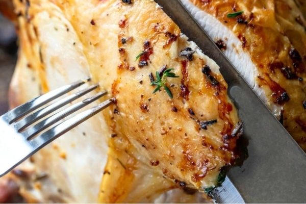 Slicing turkey breast with a knife and fork. 
