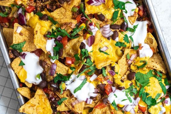 Nachos in a baking dish with sour cream on top.