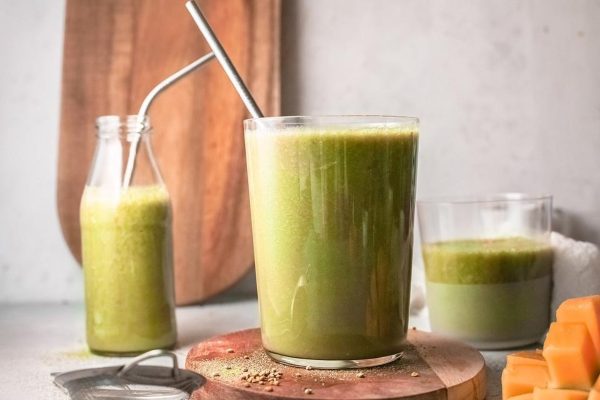 A glass of Mango Banana Matcha Smoothie with a stainless steel straw.