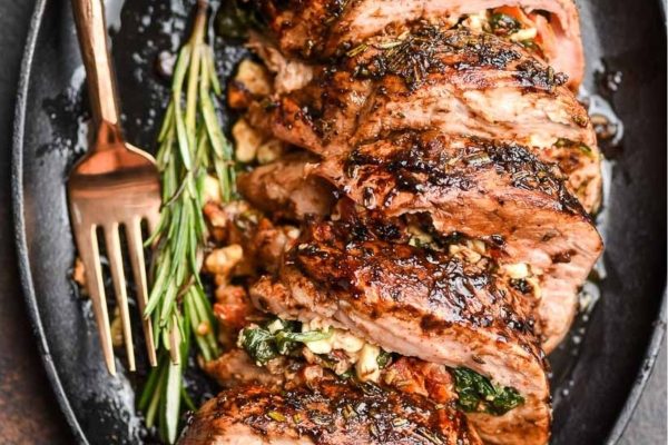 Mediterranean Stuffed Pork Tenderloin on black serving plate.