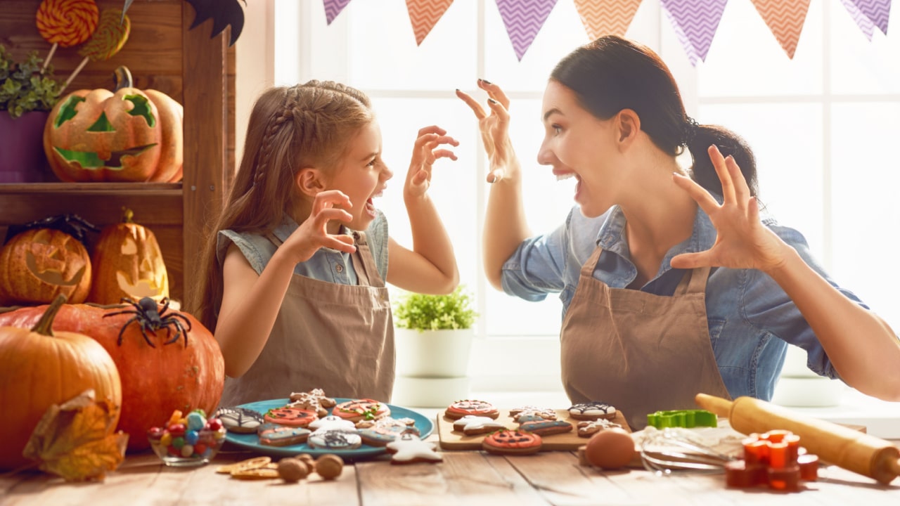 Mother and her daughter making Halloween cookies.