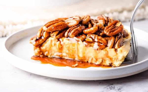 Pecan Pie Cheesecake with sauce and topped with pecans