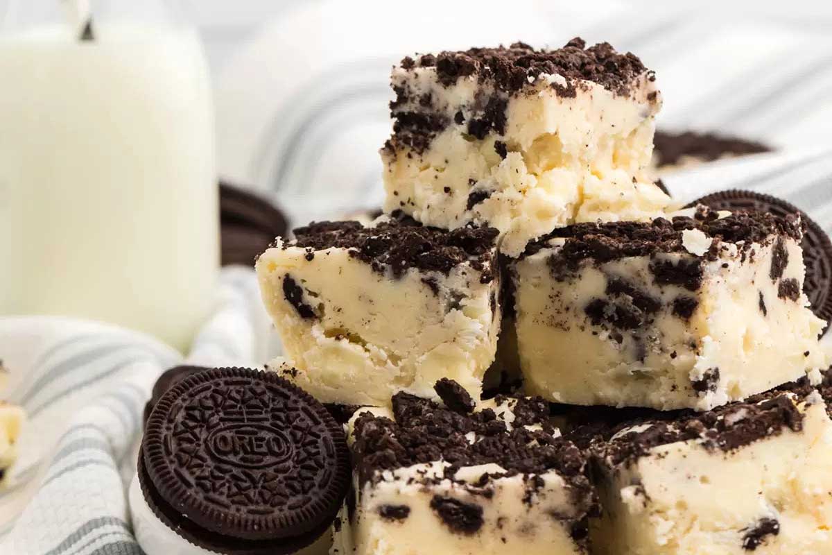 Oreo fudge stacked up with a glass of milk.