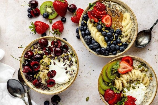 Three bowls of oats with fruit, berries and yoghurt.