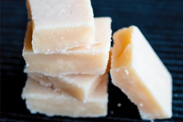 A pile of squares of sugar on a black surface.