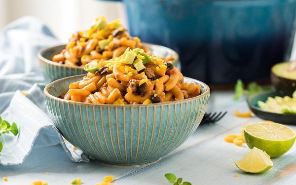 Cheesy pasta and meat in two blue bowls.