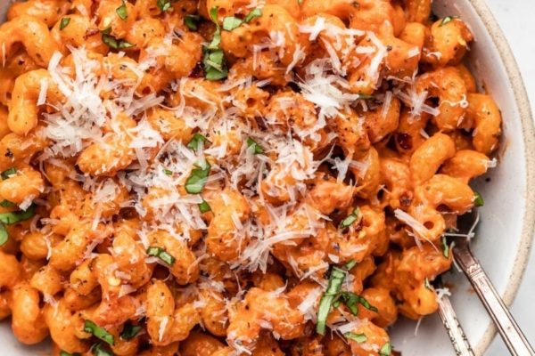 A bowl of pasta with tomato sauce and parmesan cheese.