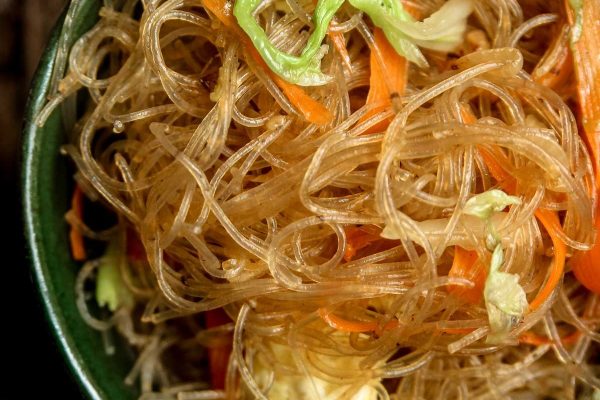 Pad Woon Sen (Thai Glass Noodle Stir Fry). on a black plate.