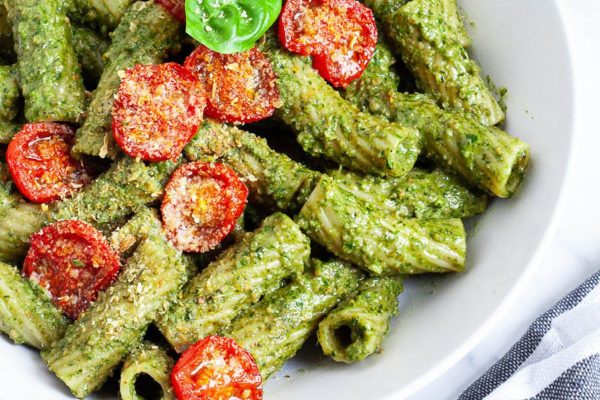Pasta with pesto sauce in a white bowl.
