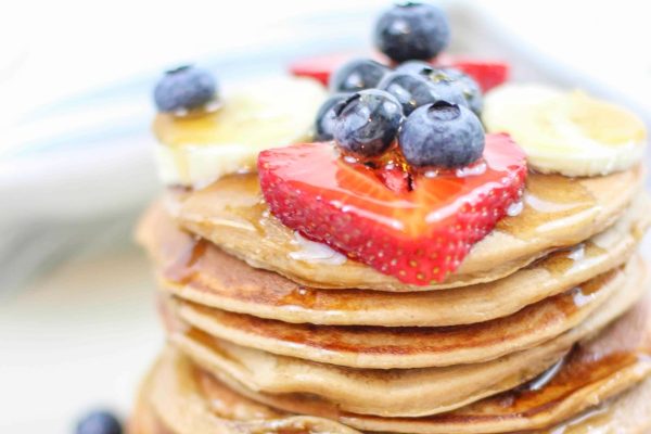 A stack of pancakes with berries and blueberries on top.