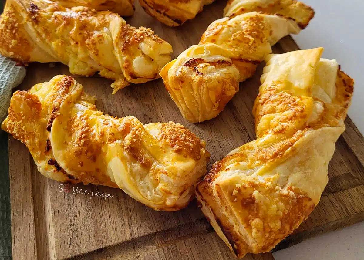Puff pastry cheese straws on a cutting board.