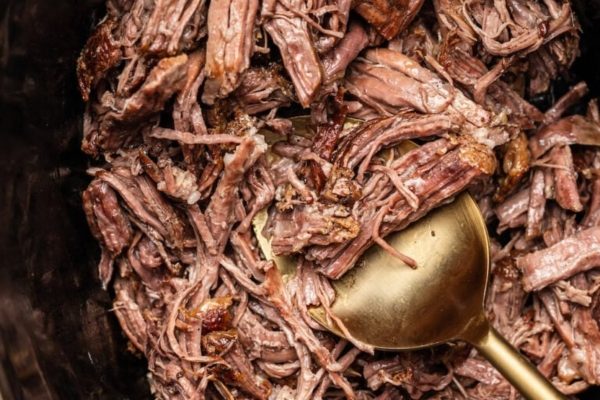 Pulled beef in a dish with a serving spoon. 
