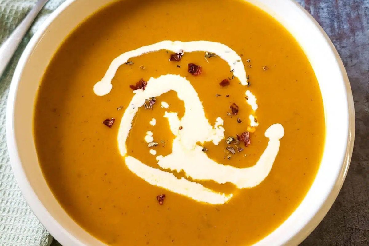 Pumpkin And Sweet Potato Soup in a bowl with cream drizzle.