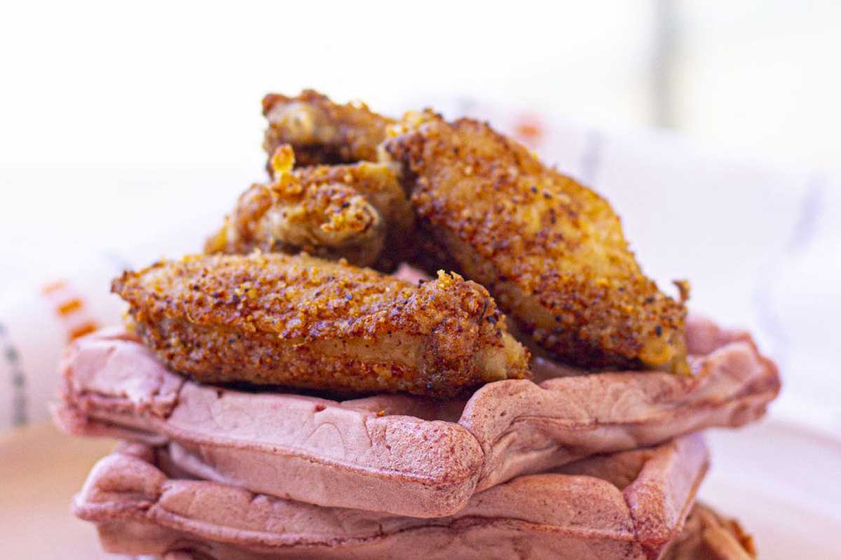 Crispy golden brown chicken wings on a layer of waffles.
