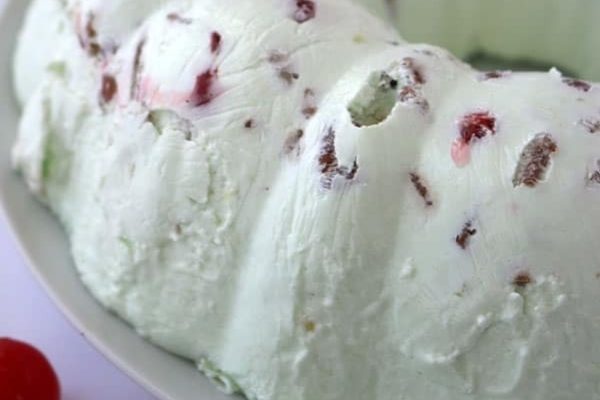 A white bundt cake with cherries on top.