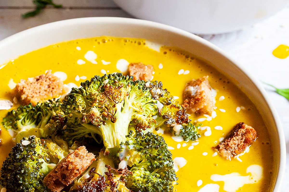 A bowl of soup with broccoli and croutons.