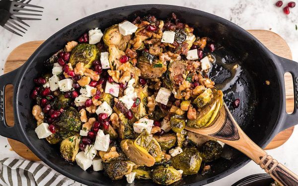 Roasted Brussels sprouts on a black skillet with wooden spoon.