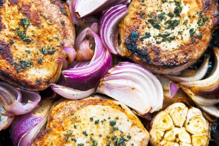 Pork chops in a skillet with onions.
